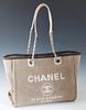 Chanel Front Logo Deauville Tote Shoulder Bag, in beige canvas and leather accents with silver hardware, the magnetic snap closure opening to a dark b