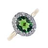 A tourmaline and diamond cluster ring. The oval-shape green tourmaline reverse-faceted cabochon, wit