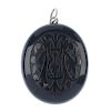 A late Victorian jet locket. Of oval-shape outline, the front carved to depict a monogram, opening t
