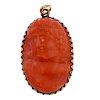 A coral pendant. The oval coral panel carved to depict the profile of a bacchante, within a scallope