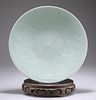 A CHINESE CELADON DISH, circular, carved floral decoration,