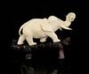 Japanese carved ivory elephant in a walking pose, with a tusk in it's trunk, on hardwood base, eleph