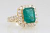 Lady's 14K Yellow Gold Dinner Ring, with a 2.97 carat emerald atop a conforming border of round diamond, the shoulders of the band also mounted with r