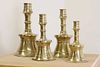A graduated set of four bell-shaped brass candlesticks,