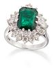 AN EMERALD AND DIAMOND CLUSTER RING, an octagonal-cut emerald in a double-c