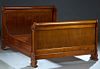 French Louis Philippe Carved Walnut Double Bed, 19th c., the curved scrolled post headboard, on flat pilasters, to stepped block feet, to wooden brack