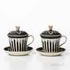 Two Wedgwood Black Jasper Dip Covered Cups and Saucers, England, 19th century, engine-turned striping and with applied white floral finials, floral fe