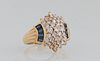 Lady's 14K Yellow Gold Dinner Ring, the top with five rows of graduated round diamonds, flanked by two arched rows of blue baguette sapphires, over ri